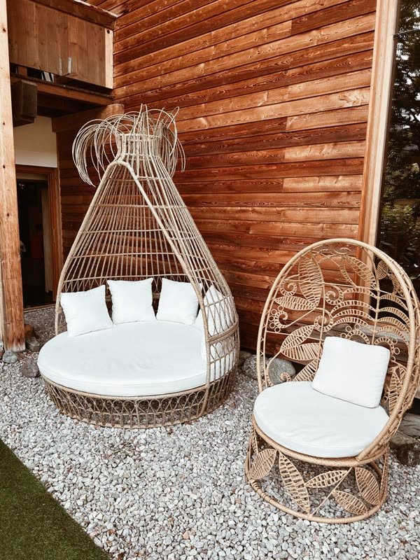Geflochtene Lounge-Möbel auf der Terrasse vor der Holzfassade