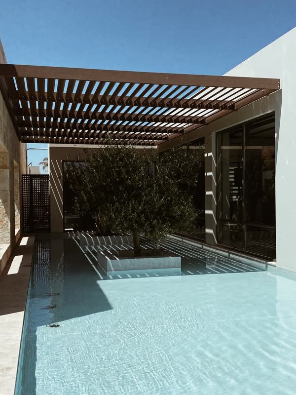 Privater Pool mit Olivenbaum unter einer Holzpergola