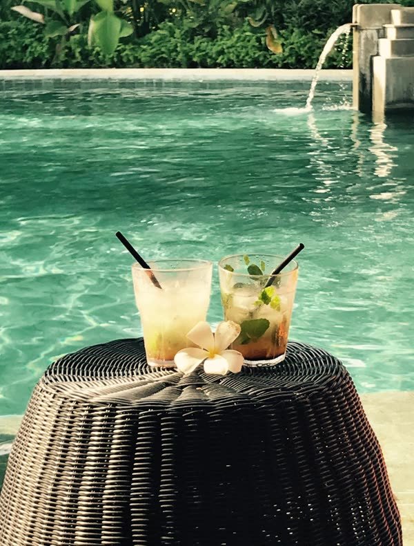 Zwei Cocktails auf einem Beistelltisch am türkisfarbenen Pool
