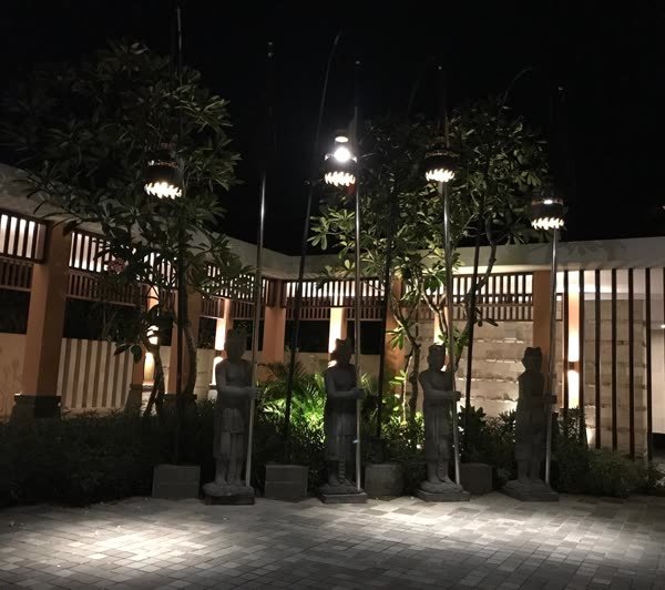 Steinfiguren und Laternen im beleuchteten Innenhof bei Nacht