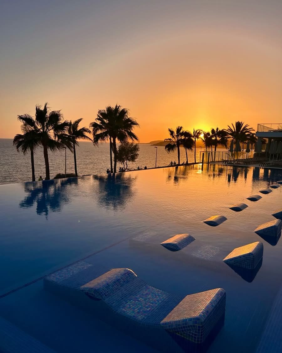 Infinity-Pool bei Sonnenuntergang zwischen Palmen