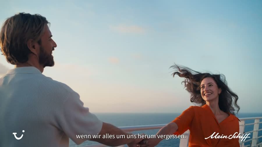 Paar an der Reling eines Kreuzfahrtschiffs im Abendlicht